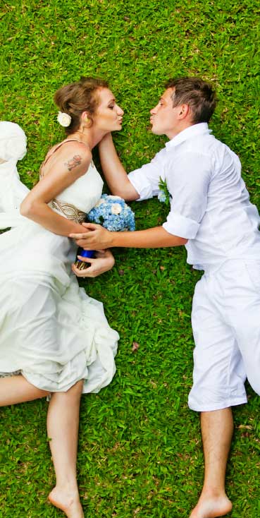 Romantic moment of bride and groom lying on the grass after their wedding at Wvec West Valley Events Complex, Phoenix, Arizona.